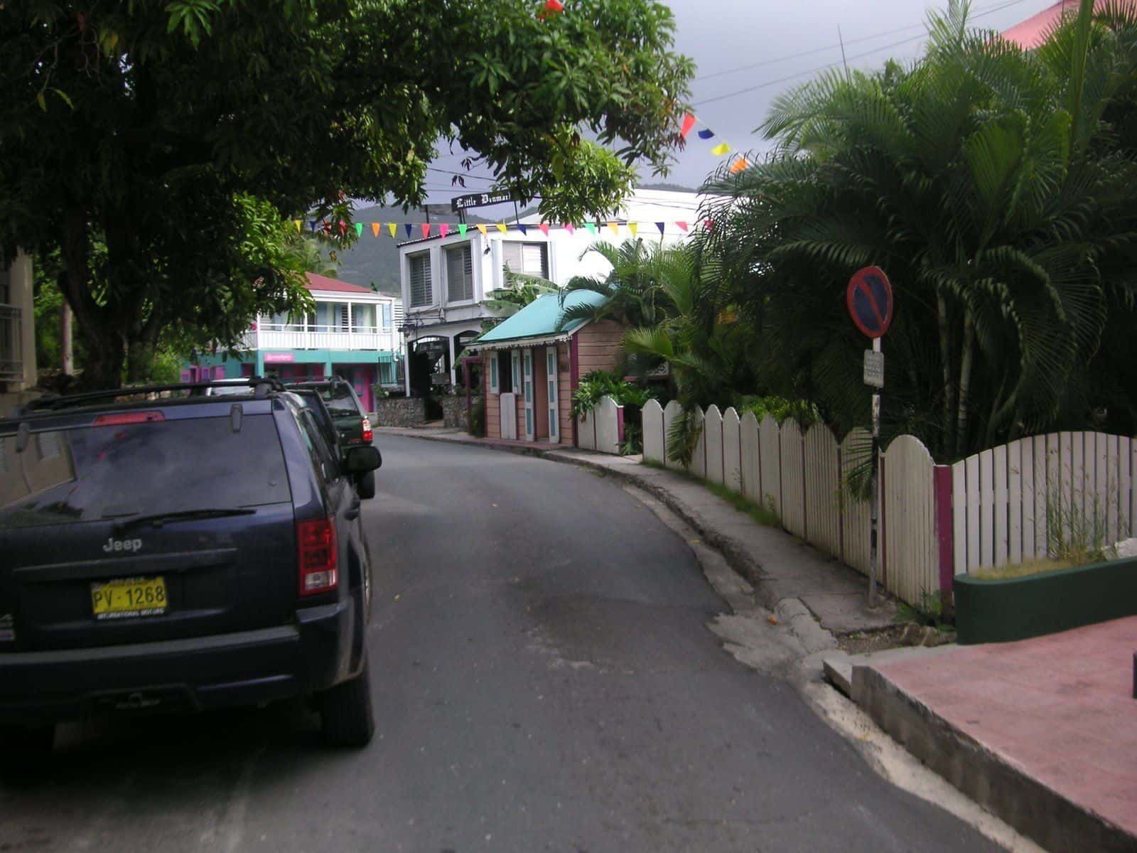 A Jeep parked on narrow Main Street in Road Town, Tortola, by old painted buildings