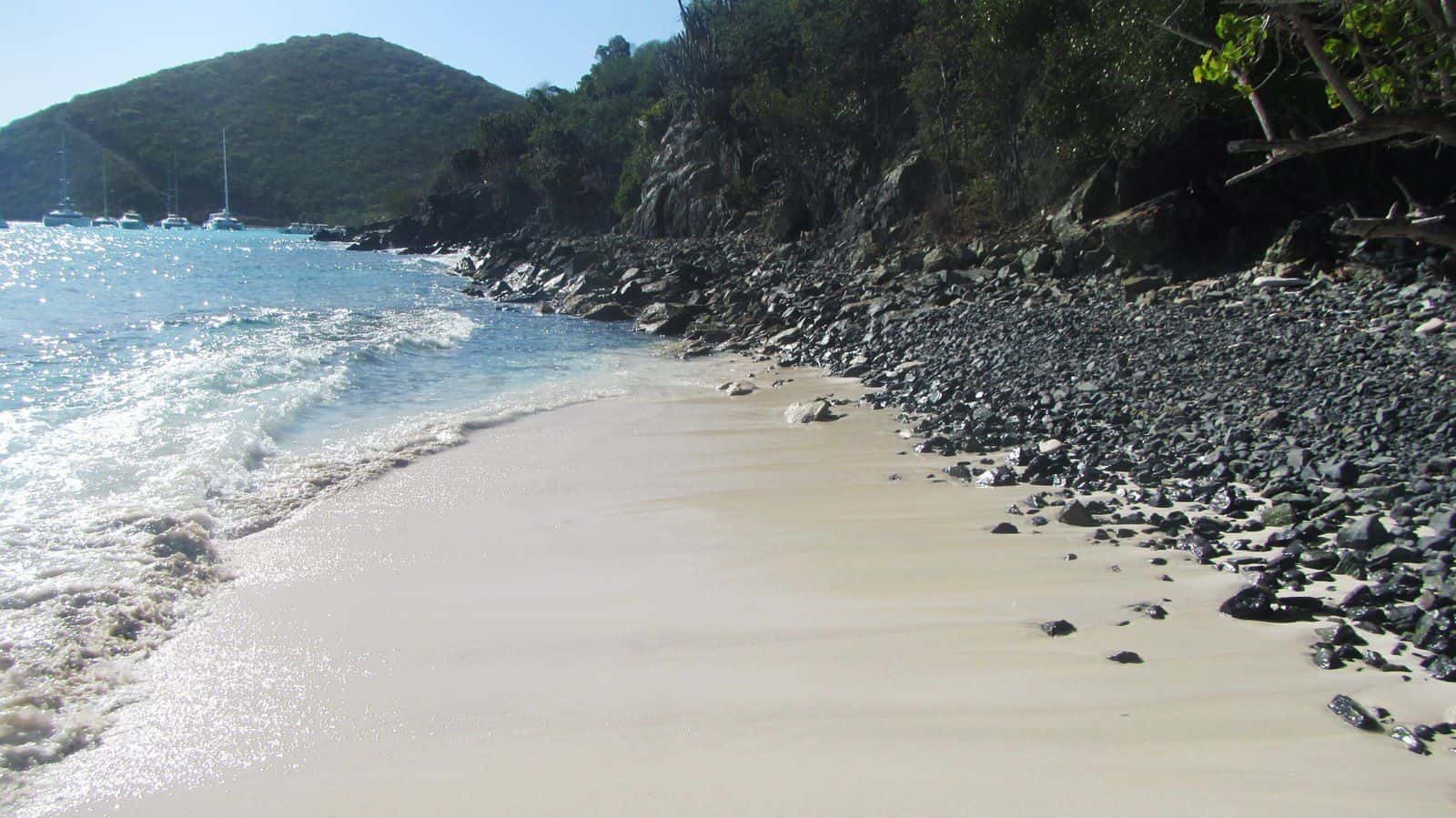 The sand and rocky edge of White Bay on Jost Van Dyke, the beach the Soggy Dollar sits on