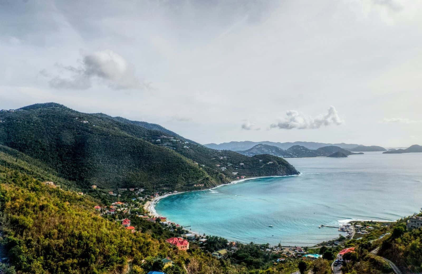 Cane Garden Bay, Tortola, from the hillside: the curve of the beach, pale blue water, green ridges