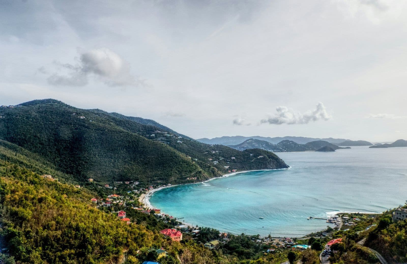Cane Garden Bay, Tortola, from the hillside: the curve of the beach, pale blue water, green ridges