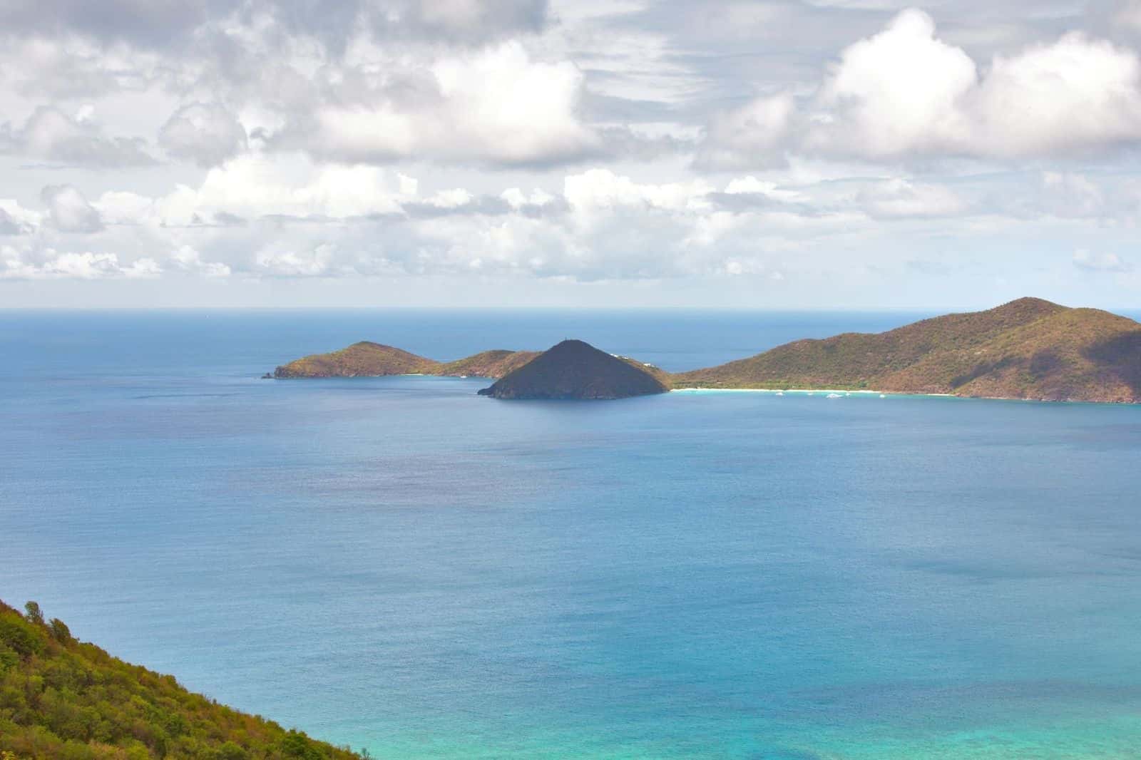 View from a Tortola hillside over blue water to a chain of small green islands under scattered cloud