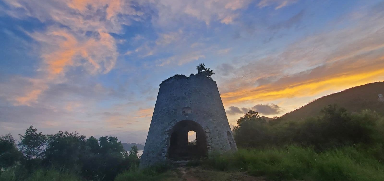 The stone windmill tower on Peace Hill at sunrise, above the trailhead for the Denis Bay path.