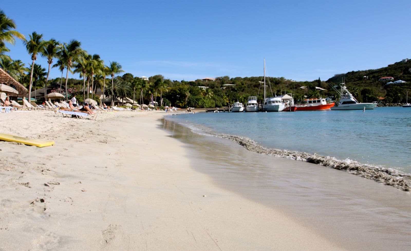 Lounge chairs and thatched umbrellas under palms along the sand at Great Cruz Bay, St. John, in March 2009.