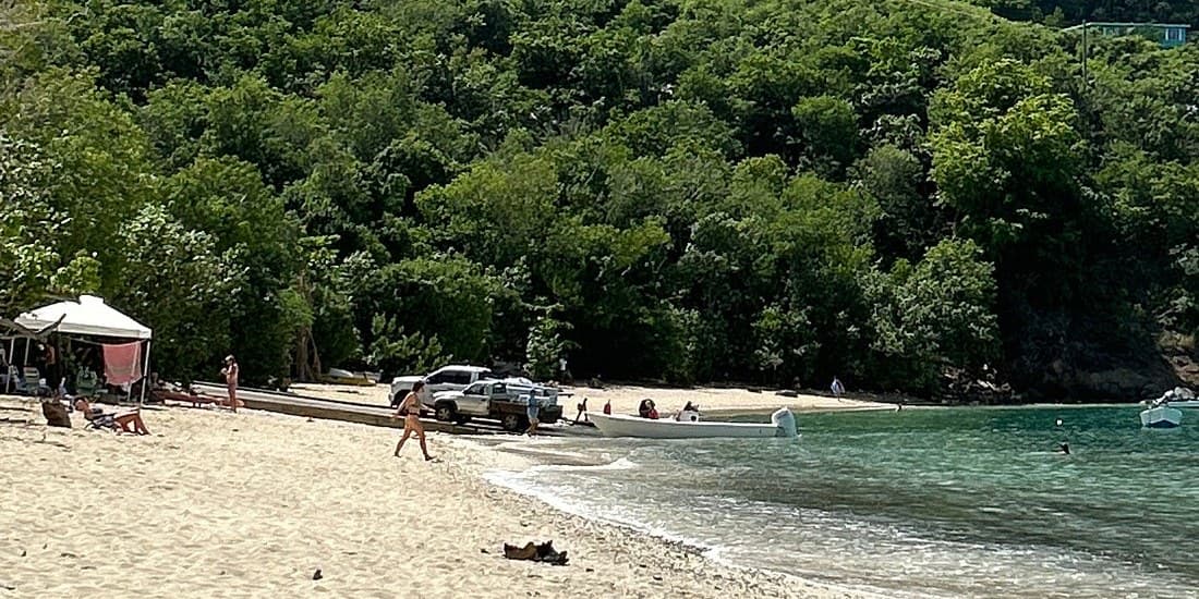 Hull Bay, St. Thomas: coarse sand, a small boat at the water's edge and forest down to the shore.