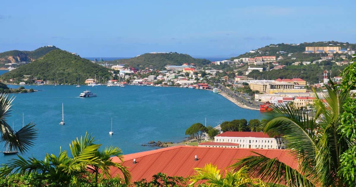 Charlotte Amalie harbor, St. Thomas, framed by palms and a red roof, with boats at anchor and the town on the hillside.