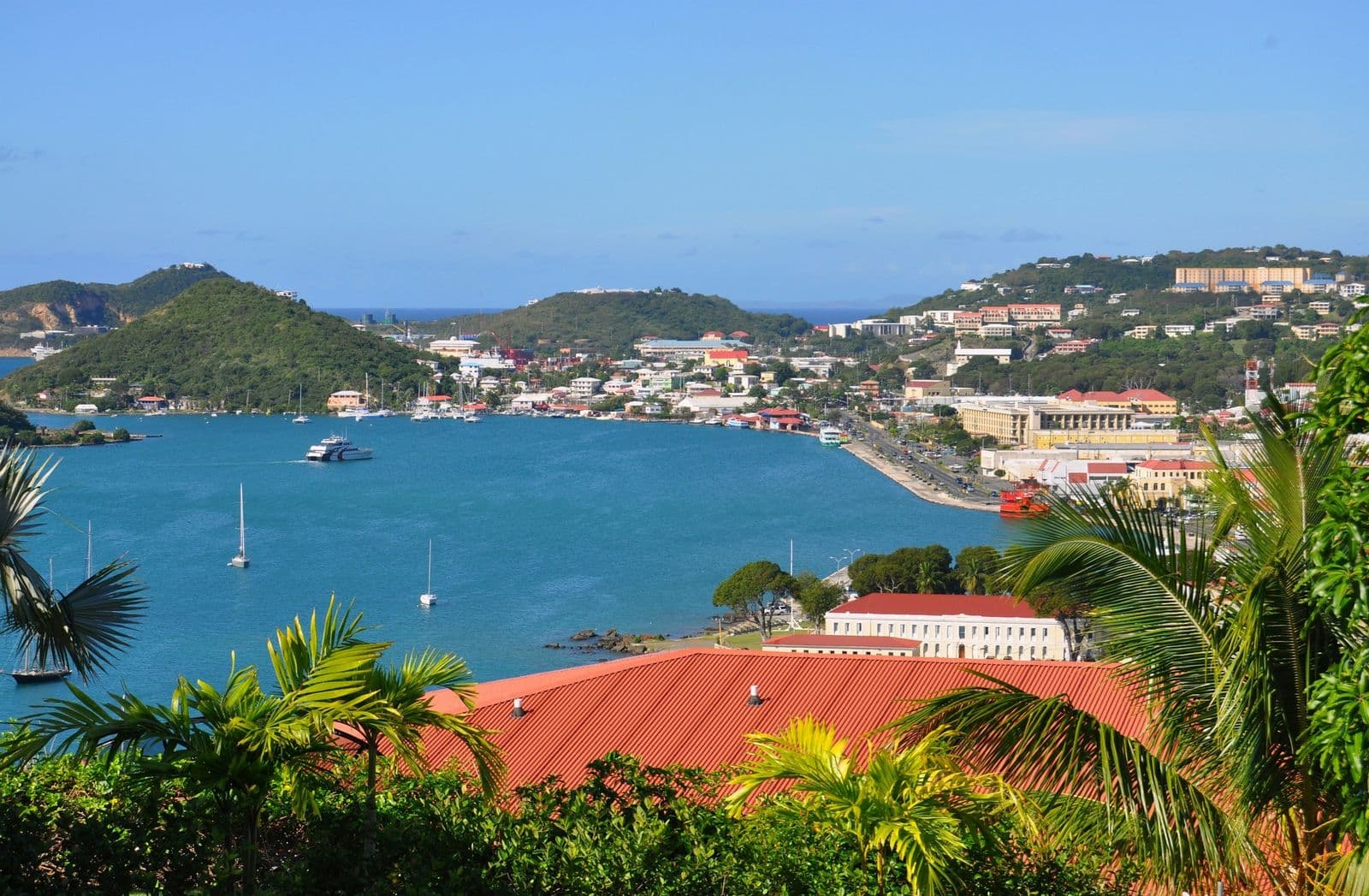 Charlotte Amalie harbor, St. Thomas, framed by palms and a red roof, boats at anchor below the town