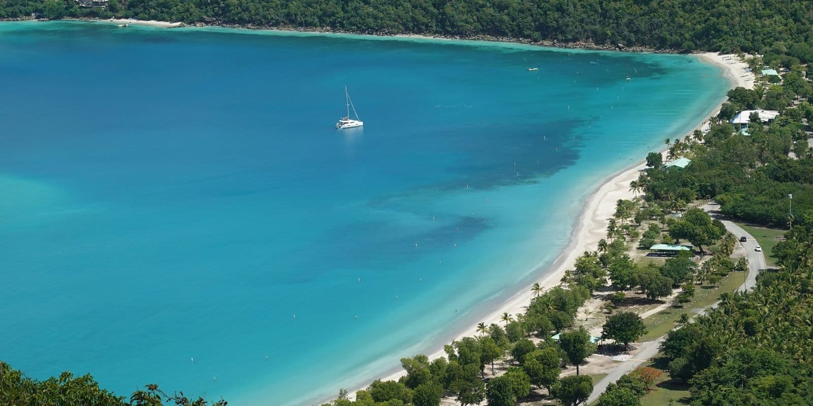 Magens Bay, St. Thomas, from Mountain Top: the full curve of the beach, a single sailboat in the bay.
