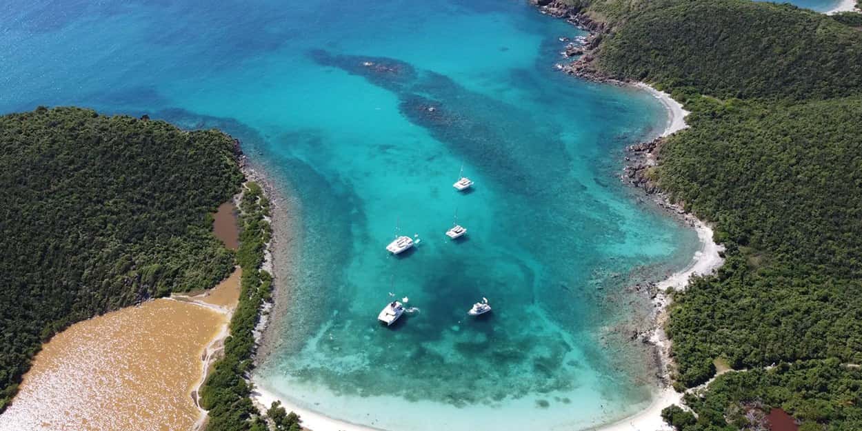 Aerial view of Salt Pond Bay, St. John: boats on moorings in a narrow turquoise bay, the salt pond at left.