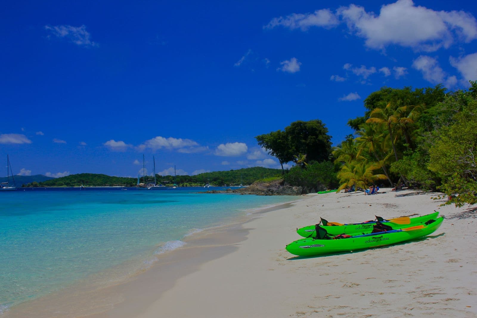 White sand curving to a rocky point at Solomon Beach, St. John, with turquoise shallows in full sun.