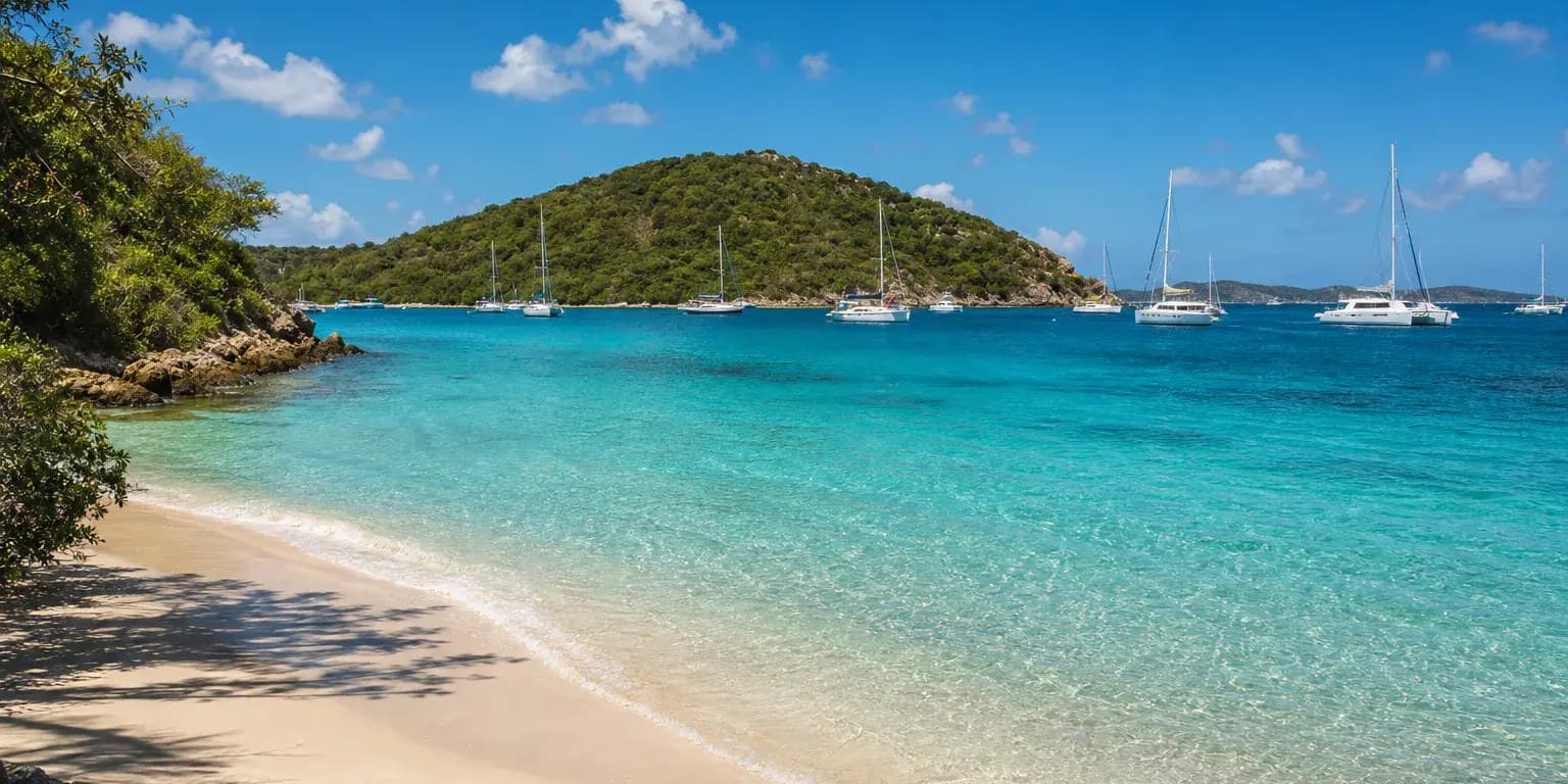 Vessup Beach, St. Thomas: sand in the shade of trees, sailboats moored off a small green island.